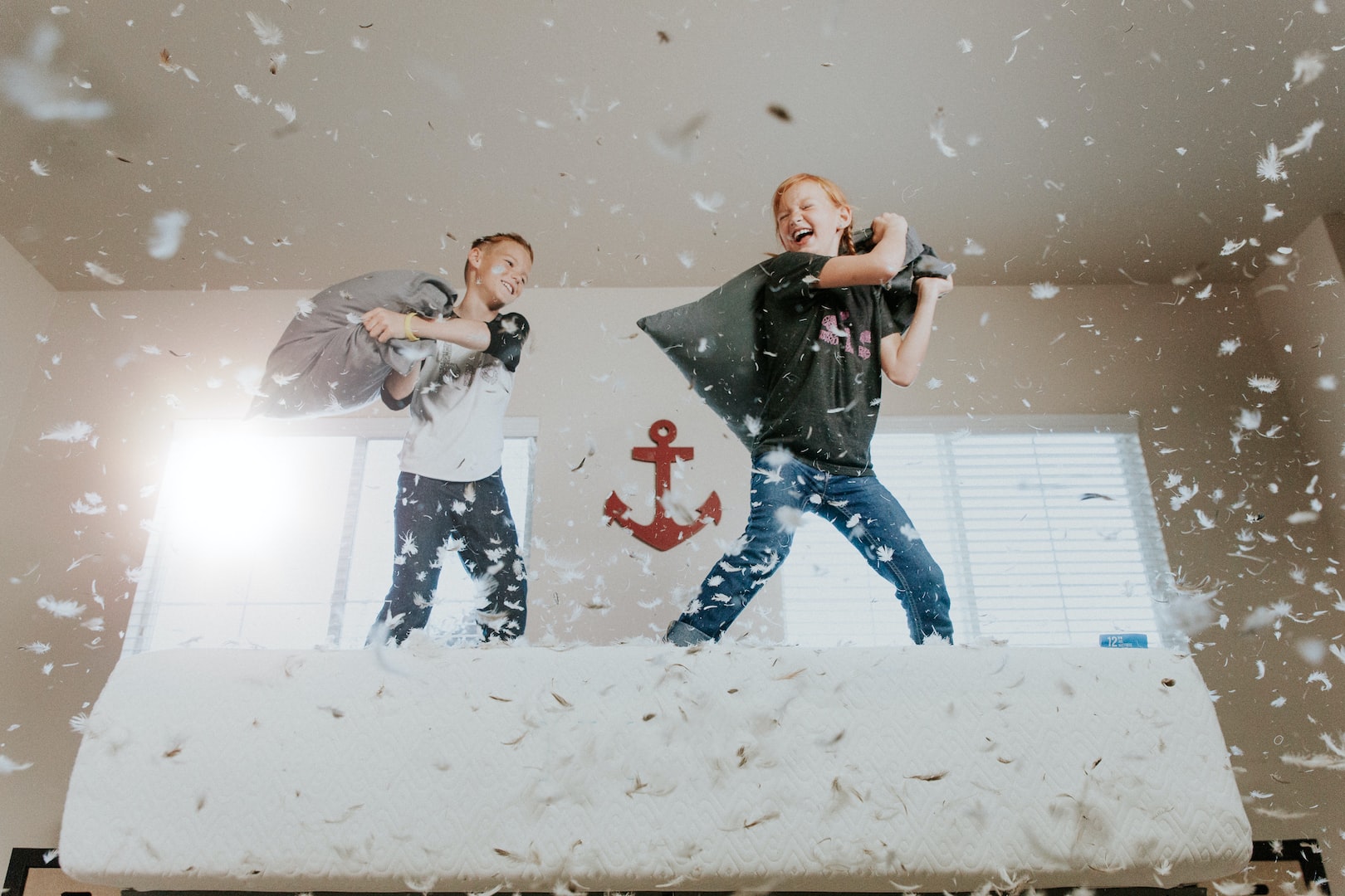 2 kids pillow fighting on a bed