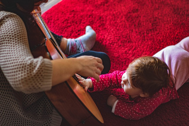 baby crawling on rug while mother plays guitar